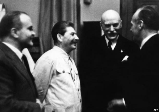 Йосиф Сталін (другий ліворуч), міністр закордонних справ СРСР В'ячеслав Молотов (ліворуч) та міністр закордонних справ нацистської Німеччини Йоахім фон Ріббентроп (крайній праворуч) під час укладання пакту Молотова-Ріббентропа. Москва, 23 серпня 1939 року